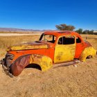 Abandoned rusty car in desert landscape with blue skies