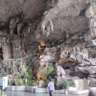 Large Seated Buddha Statue Surrounded by Smaller Carved Figures in Cave