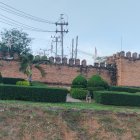 Suburban houses with brown roofs, manicured hedge, landscaped garden, and electrical towers.