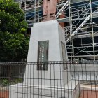 Metal robot sculpture behind fence with construction scaffolding.