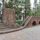 Stone ruins and arches in foggy forest with cobblestone path