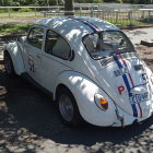 Vintage Volkswagen Beetle with sunroof and wooden accents parked outdoors.