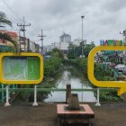 Desolate amusement park with rusty roller coaster and overgrown vegetation.