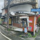 Abandoned two-story house with cluttered yard and overgrown vegetation