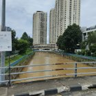 Turbulent river with moss-covered wall and modern skyscrapers under cloudy sky