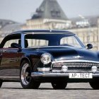 Vintage Black Car with Gold Wheels on Cobblestone Street & Historical Buildings