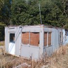 Rustic cabin with peeling white paint in lush garden