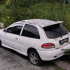 Rusty white car parked on grass, another car in background