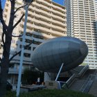 Futuristic blue hover vehicle among trees and skyscrapers on clear sky with visible planet