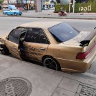 Luxurious Golden Car with Elaborate Designs Parked by Modern Building