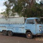 Vintage Blue Van with Surfboards Parked in Grassy Area