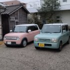 Compact cars parked near traditional Japanese architecture with electric car charging station.