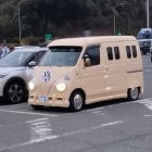 Vintage Volkswagen bus with wooden paneling parked next to green car at gathering