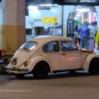 Vintage car in post-apocalyptic scene with industrial structures and glowing "MD" sign