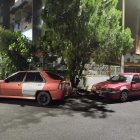 Group of people admiring modified pink and black cars on city street at night