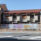 Multicolored dilapidated houses with debris and pot near street.