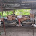 Vintage attire person between classic cars and old building in stylized photo