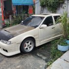 Custom Wide Body Sedan with Gold Rims and Graffiti Decals on City Street