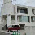 Unique modern building with organic shapes and holes, resembling Swiss cheese, red van parked in front