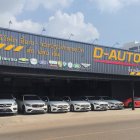 Vintage cars parked under corrugated metal roof in rustic tropical setting