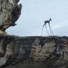 Two people at rocky cliff with waterfall, camera on tripod