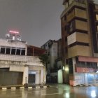 Rainy Evening Scene: Wet Streets, Red Traffic Lights, Silhouette at Bus Stop