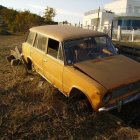 Vintage golden car parked near shore with yacht at sunset