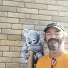 Woman with braid holding koala, textured wall, two koalas.