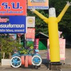 Smiling group around person in yellow suit under colorful sign