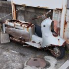 Decaying abandoned scooter with sidecar in dry vegetation