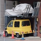 Digitally altered image of classic yellow car with futuristic structure in industrial setting