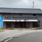 Traditional Japanese architecture with tiled roof and balcony beside parked car