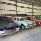 Assorted classic cars in different colors inside bright warehouse