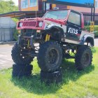 Colorful Modified Vehicle with Oversized Tires Parked on Grass