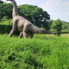 Realistic dragon statue on green hillside with person and second dragon head prop