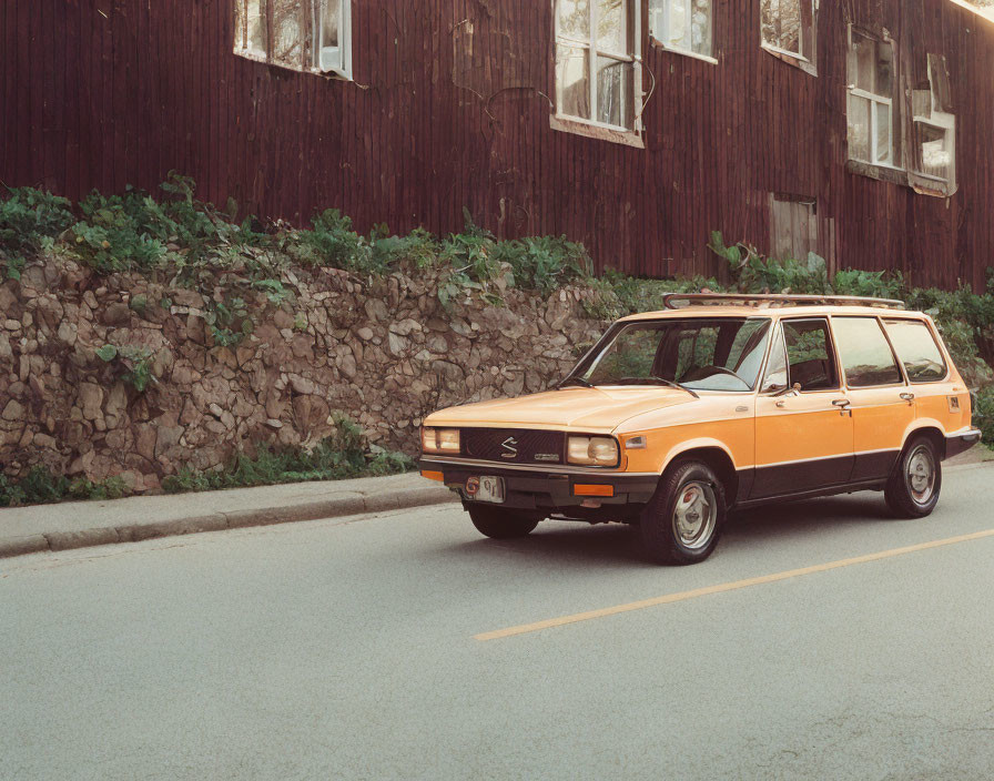 Vintage Orange Station Wagon Beside Rustic Building & Stone Wall