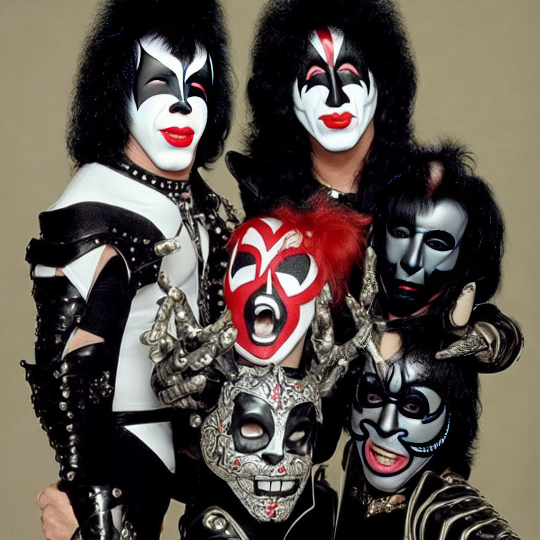 Four individuals in black and white face paint in flamboyant rock band costumes.