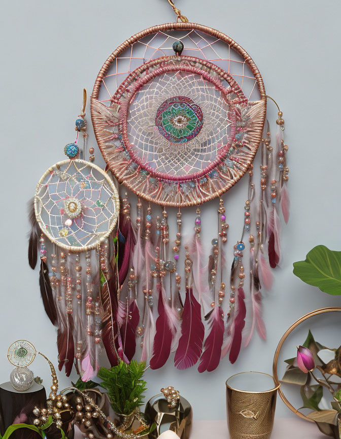 Intricate wall-mounted dreamcatcher with pink feathers and beads on grey background