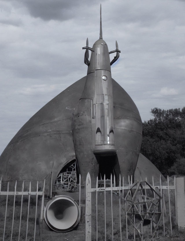 Monochrome photo of rocket-shaped structure on damaged dome under cloudy sky