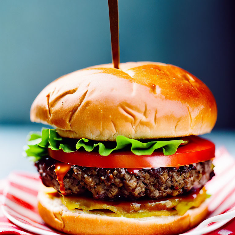 Sesame Seed Bun Burger with Lettuce, Tomato, and Pickles on Striped Nap