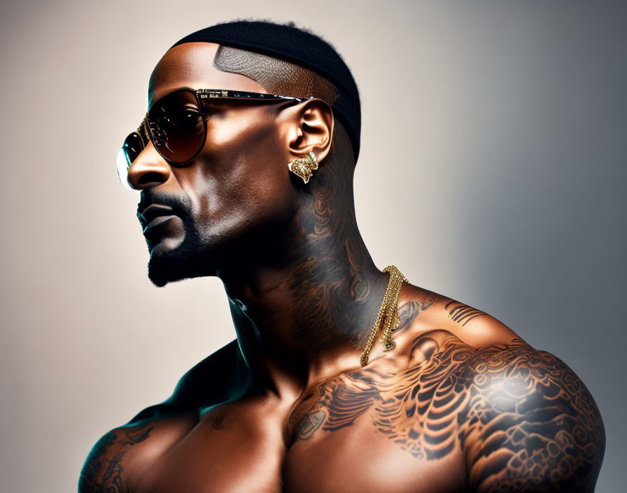 Confident man with tattoos and sunglasses in stylish accessories on warm-toned backdrop