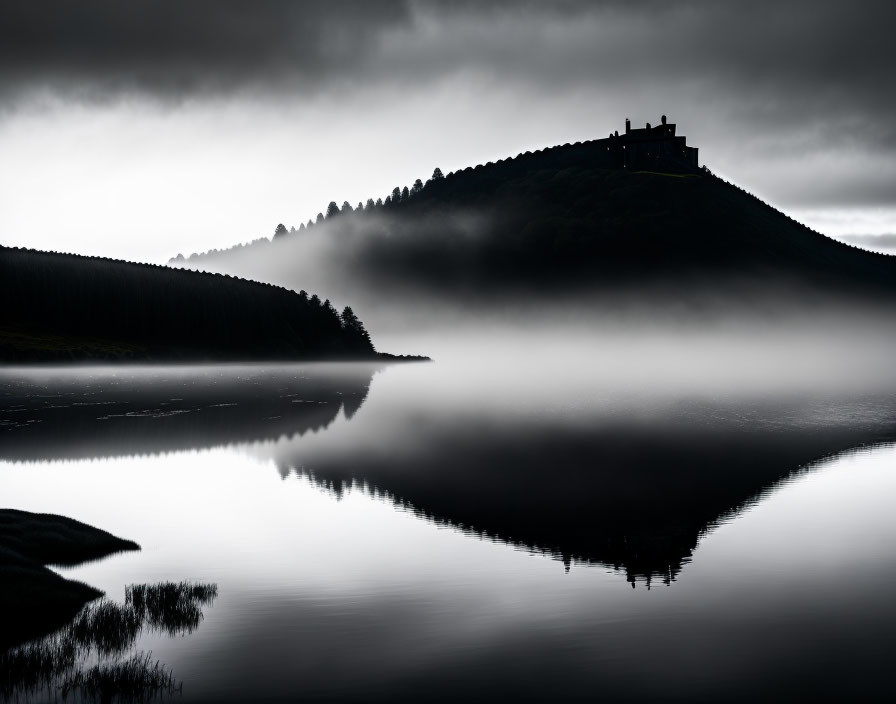 Monochrome landscape: serene lake, foggy hill, trees, building silhouette