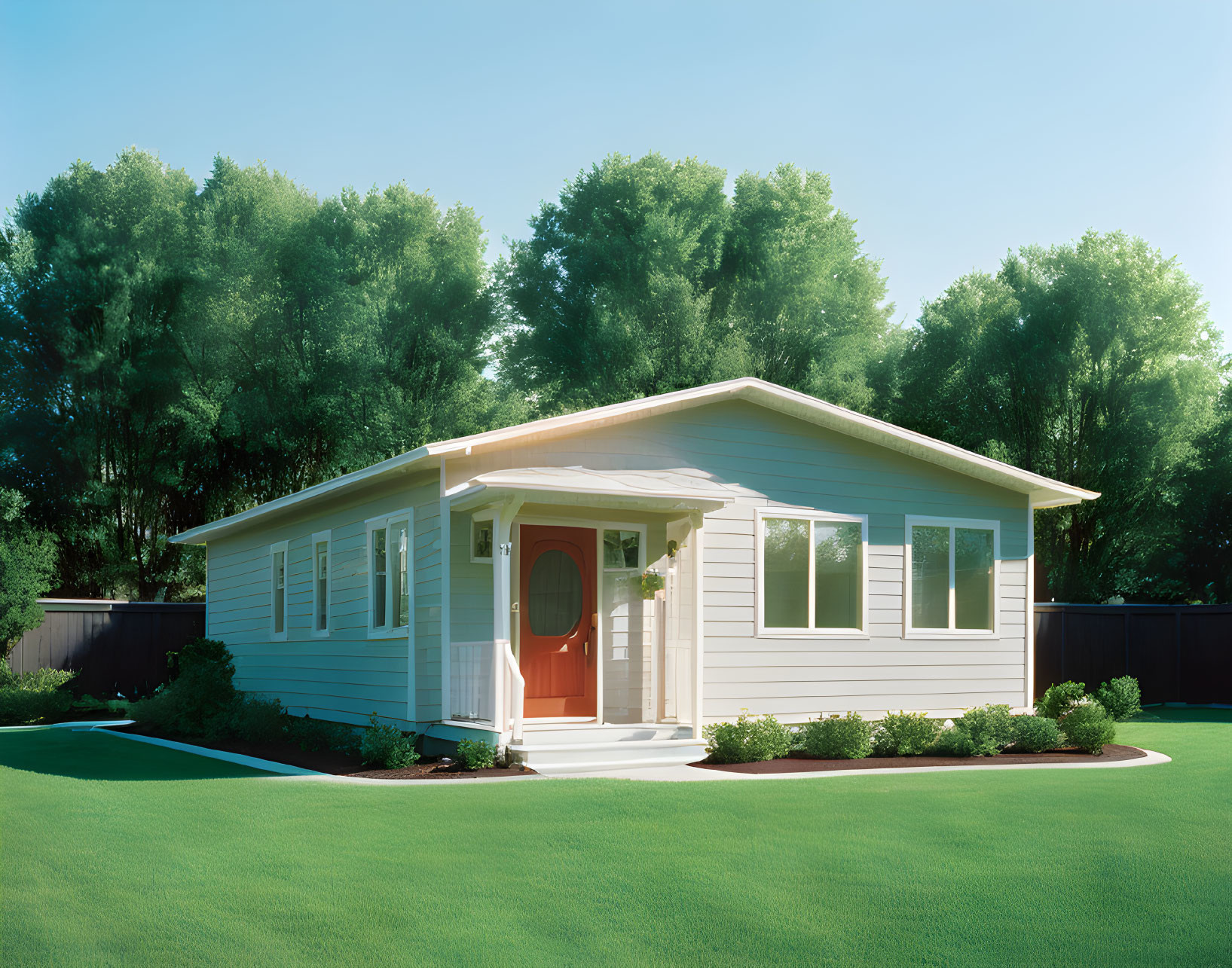 Beige siding, red door, green lawn, tall trees - One-story home under blue sky