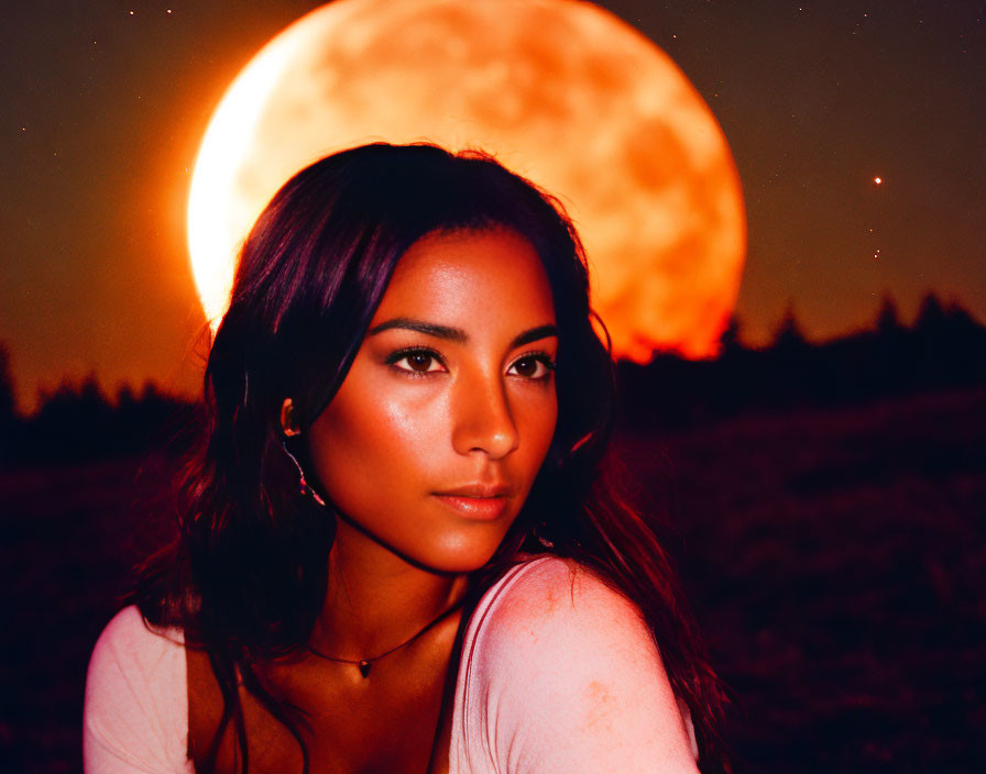 Serene woman in field at dusk with vivid moon.