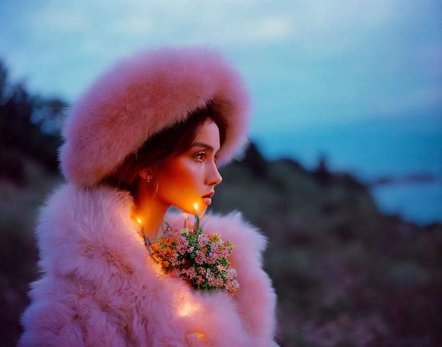 Woman in pink fur hat and coat holding flowers under twilight sky