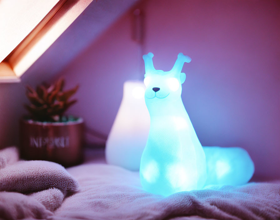 Blue snail-shaped lamp illuminating cozy bedspread with potted plant