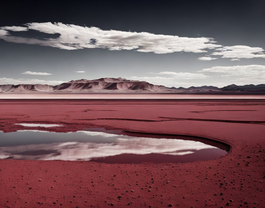 Crimson-toned landscape with sinuous water body and distant mountains