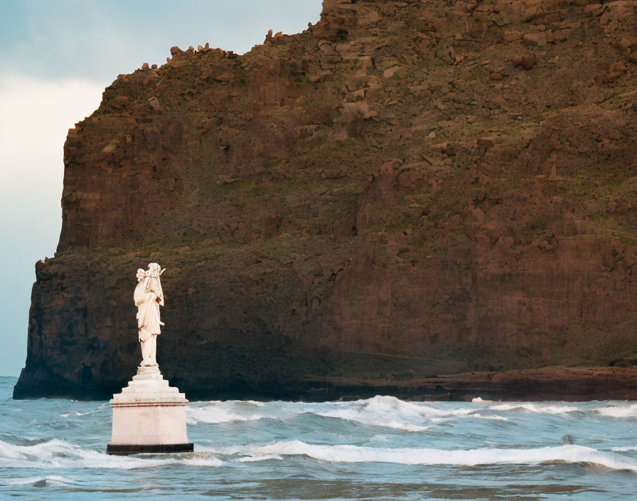 Statue on Pedestal at Sea with Crashing Waves & Cliff Backdrop