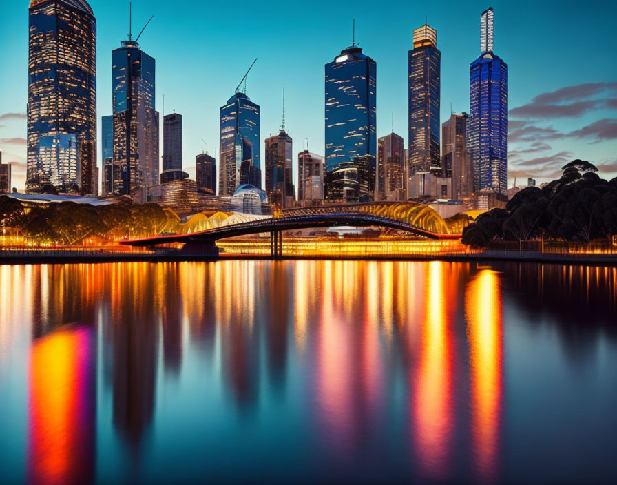 City skyline at dusk with illuminated skyscrapers and bridge reflected in water