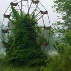 Lush garden with vibrant flowers, overgrown Ferris wheel, ornate gates in misty background